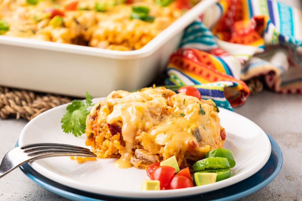 Portion of queso chicken and rice casserole on a white plate with a fork.