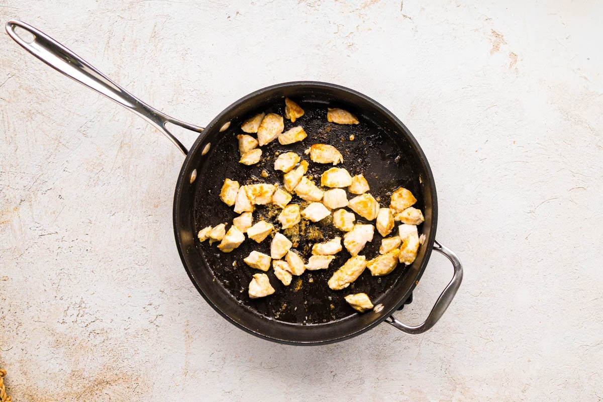 Searing the chicken pieces in a skillet.