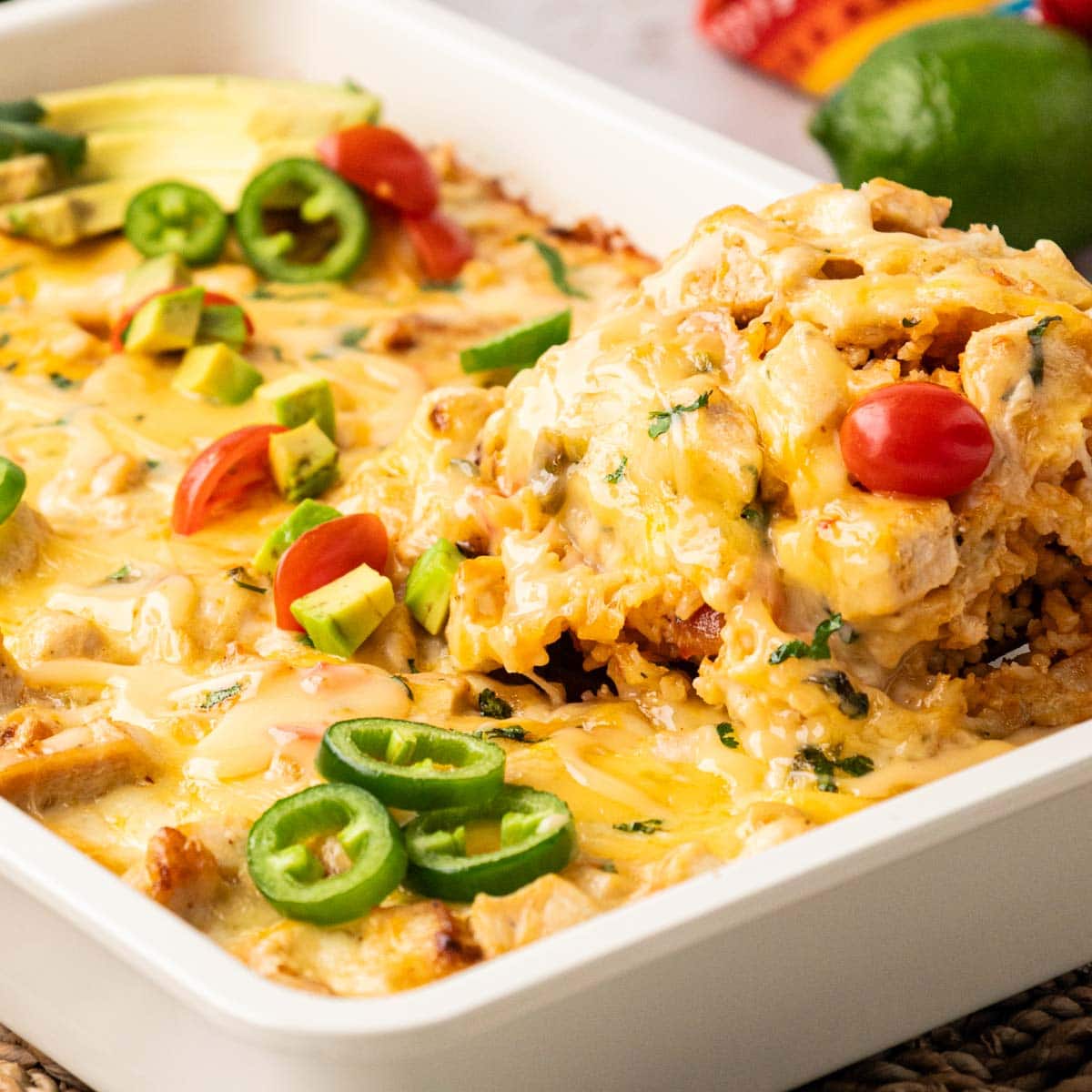 Scooping a portion of queso chicken and rice casserole from a baking dish.