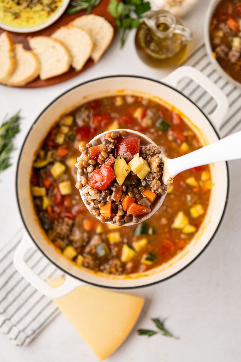 A ladle removing a serving of soup.