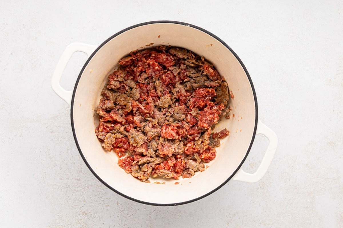 Ground Italian sausage cooking in a dutch oven.