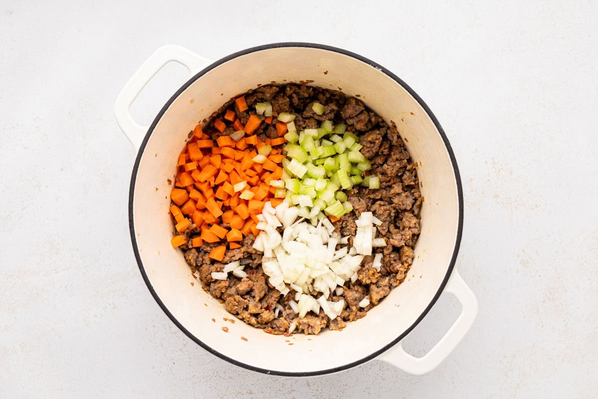 Diced carrots, onions, and celery added to the cooked sausage in the dutch oven.