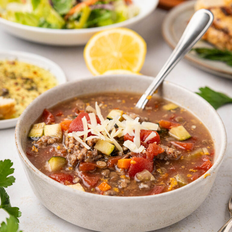 A bowl of lentil soup with Italian bread in the background.