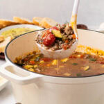 A ladle removing a serving of Italian Sausage Lentil soup.