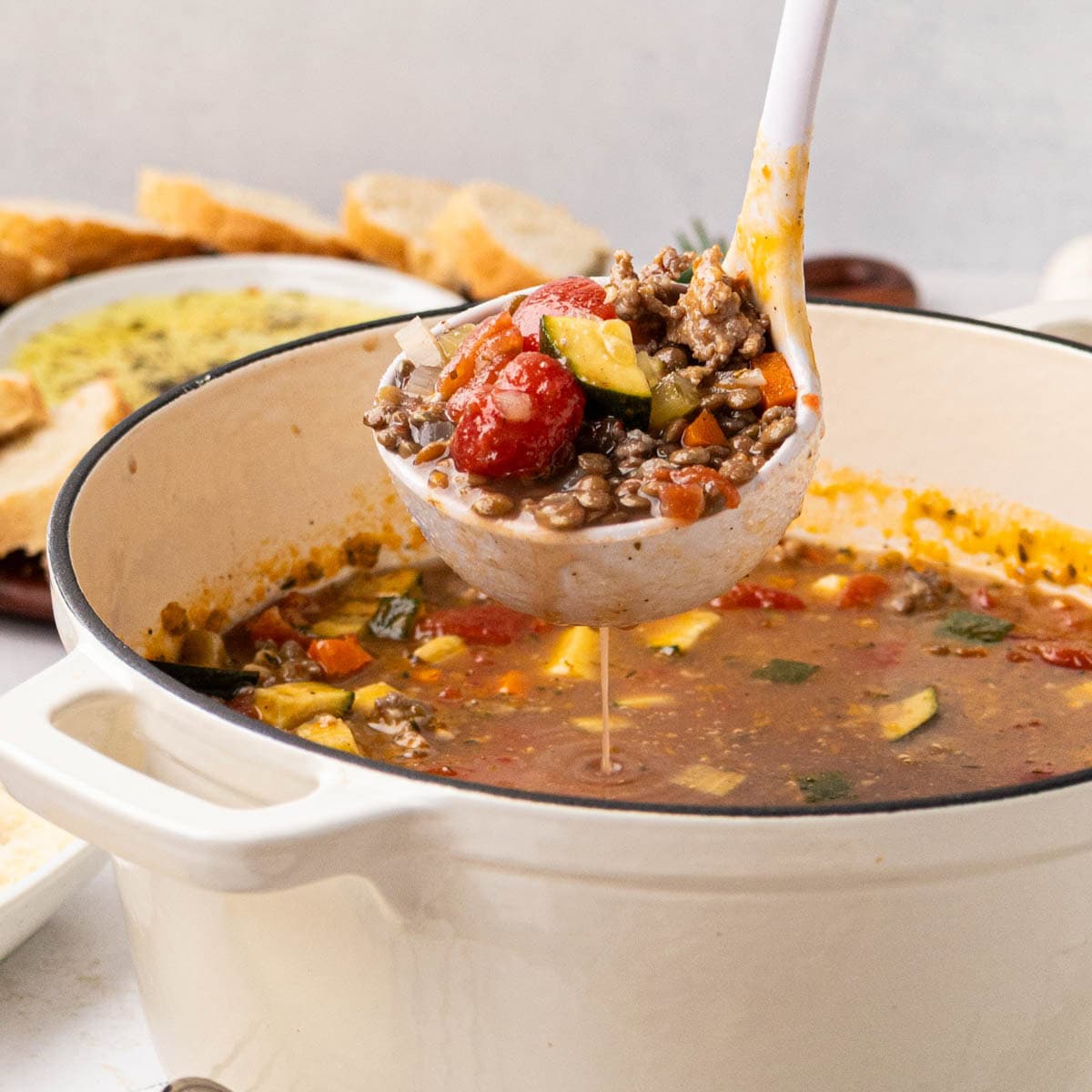 A ladle removing a serving of Italian Sausage Lentil soup.