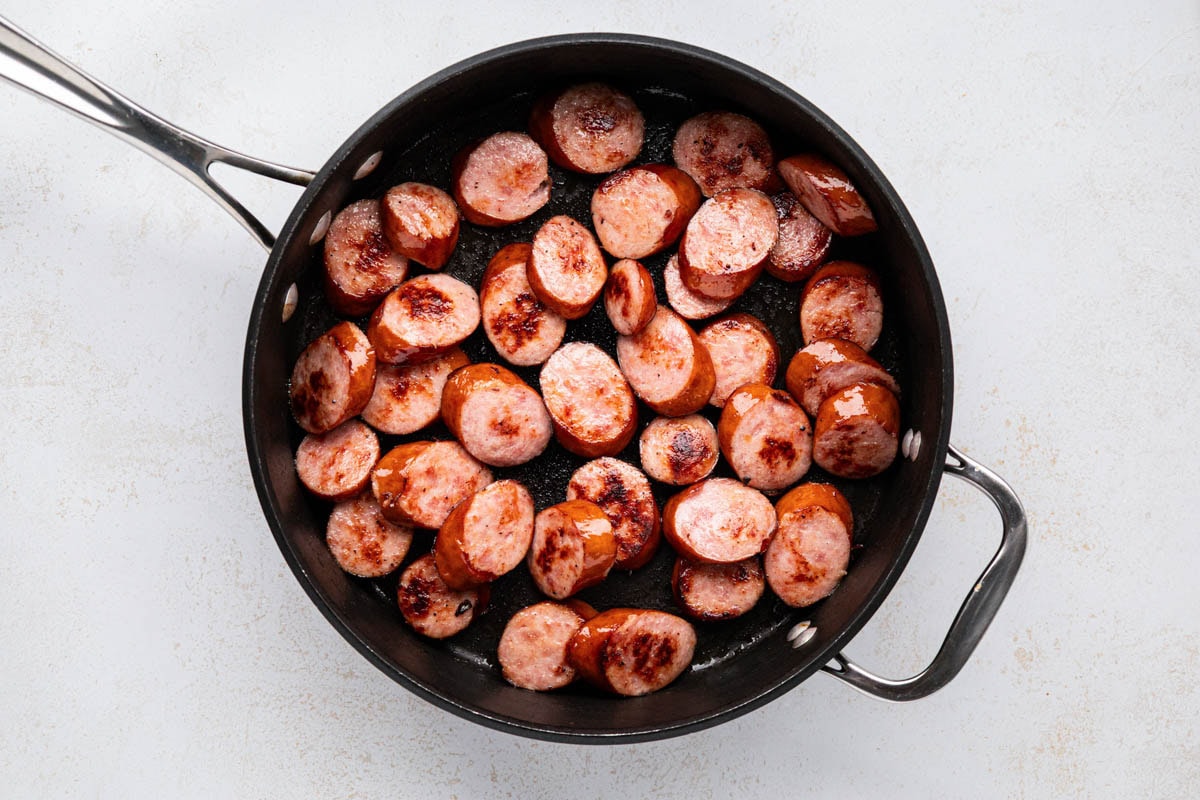 Searing sliced sausage in a skillet.