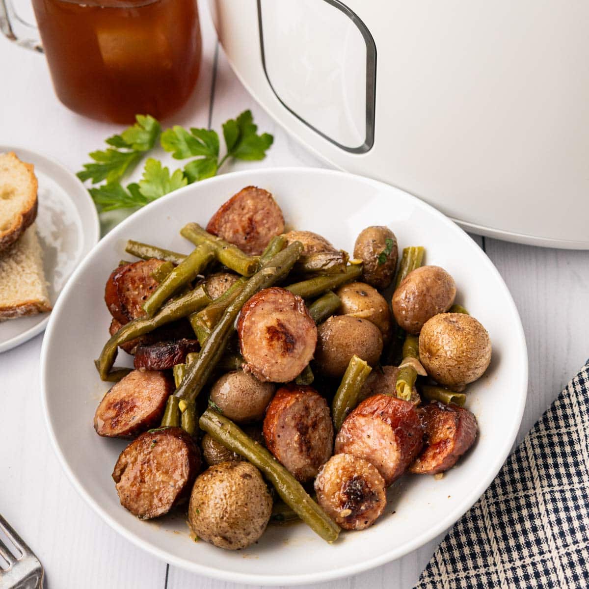 Swamp potatoes served in a white plate with iced tea and a crockpot in the background.