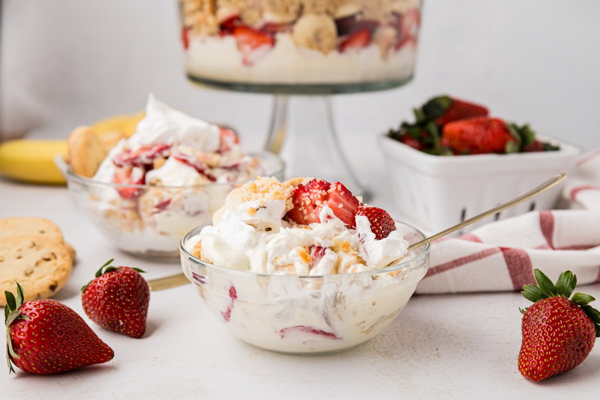A serving of strawberry banana pudding with the trifle dish in the background.