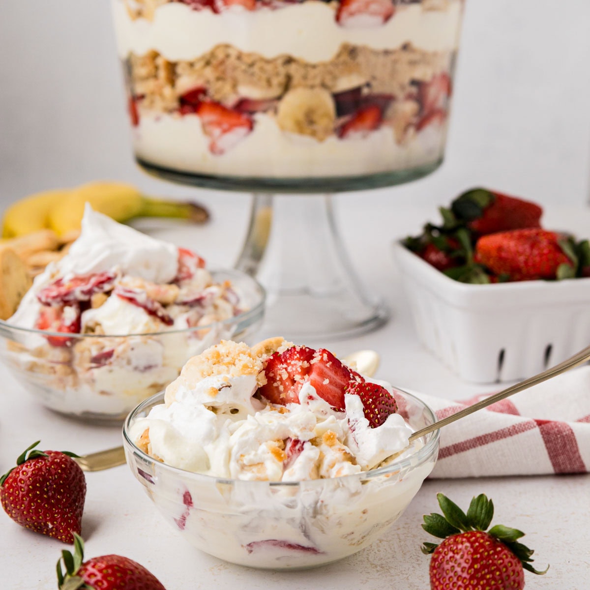 A serving of strawberry banana pudding with the trifle dish in the background.