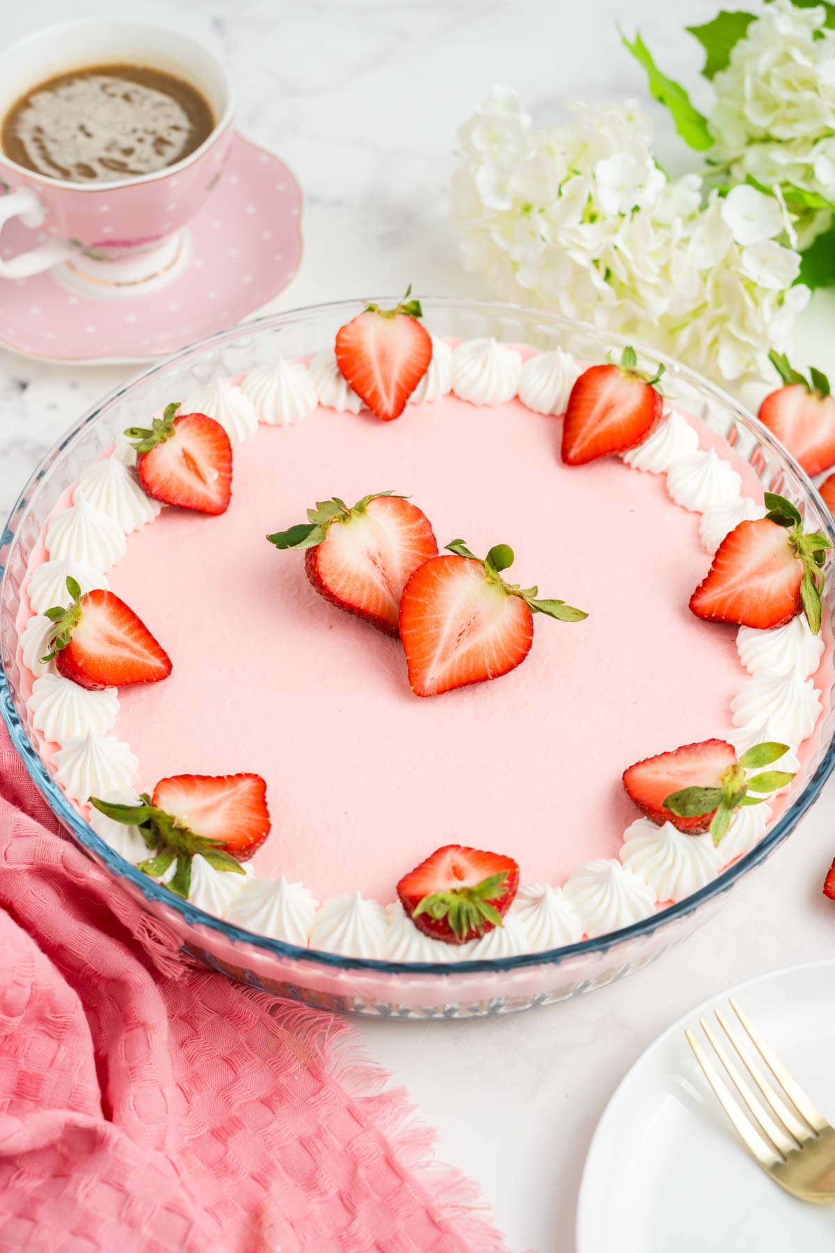 Finished strawberry jello pie in a glass pie dish, garnished with whipped cream and strawberries.