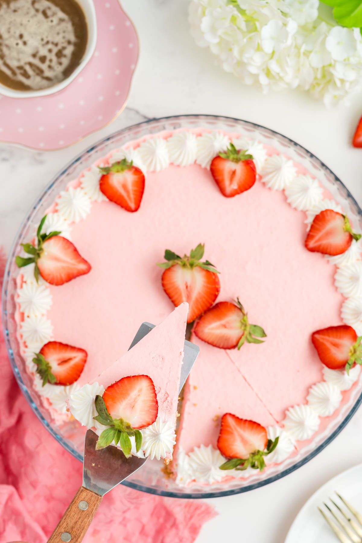 Overhead shot of strawberry jello pie with a slice of it on a spatula.