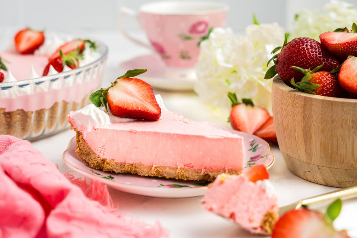 Side view of a slice of strawberry jello pie on a plate.