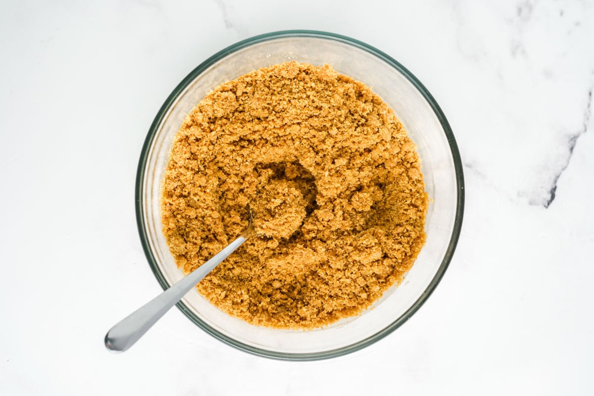 Graham cracker crumbs, melted butter, and sugar mixed together in a bowl.