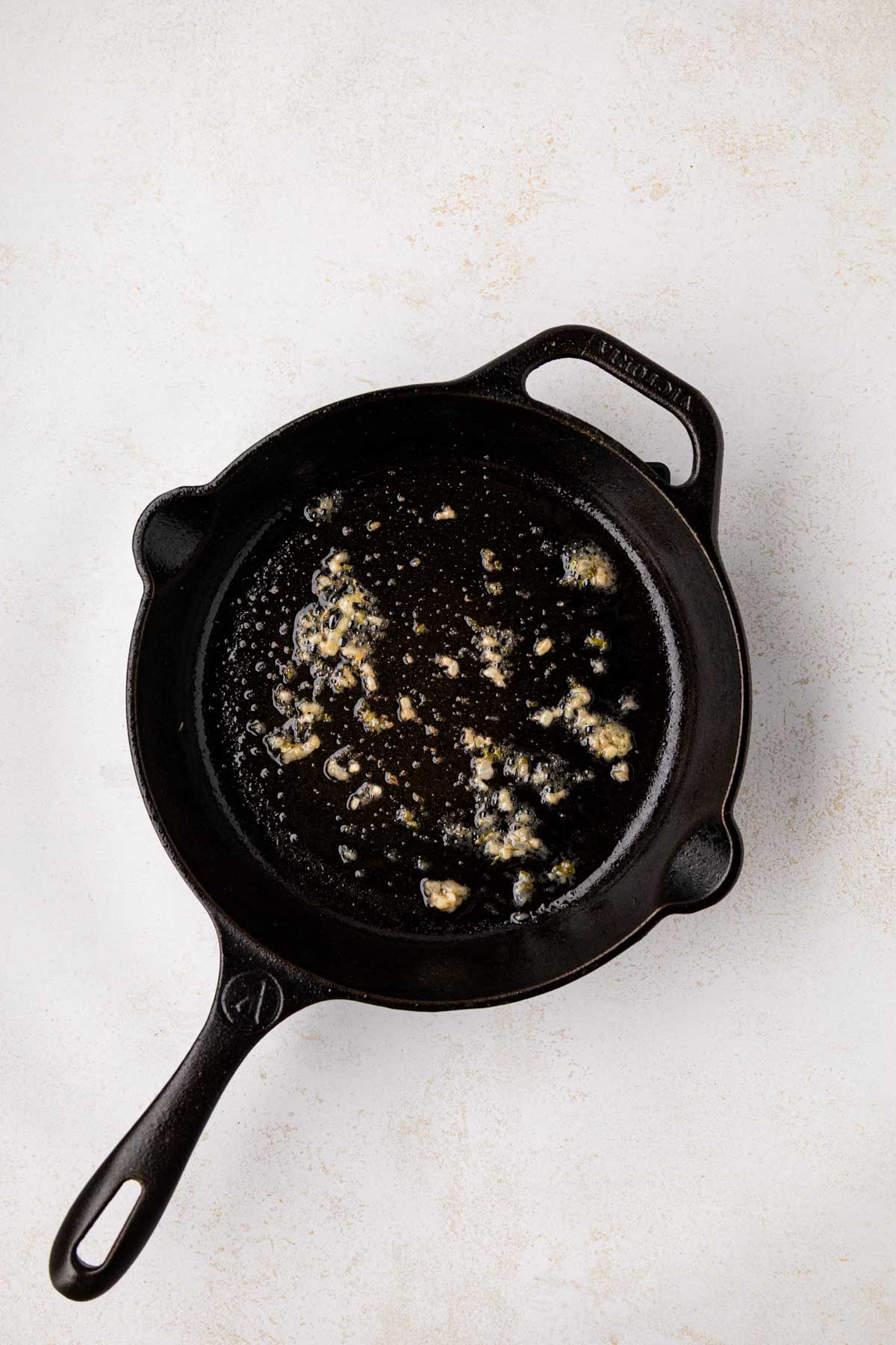 Basting oil in a cast iron skillet to coat the bottom.