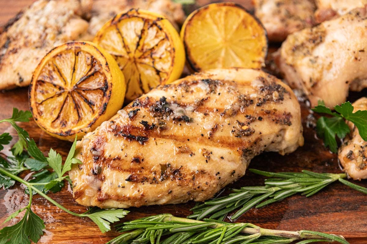Tuscan grilled chicken after being cooked on a wooden board with parsley and lemon.