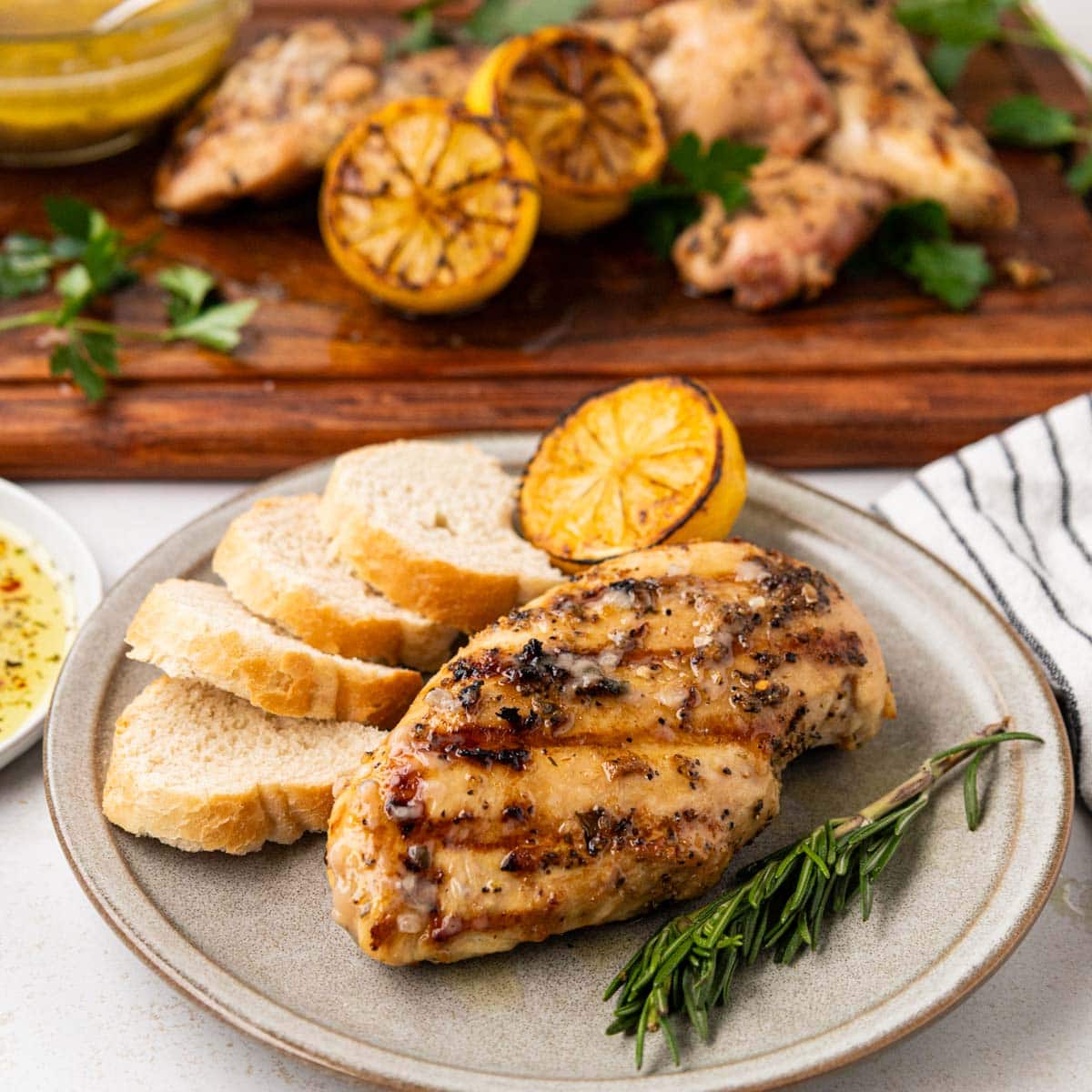 Italian grilled chicken on a plate with bread slices a charred lemon and herbs.
