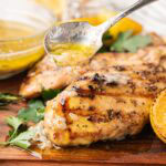 Tuscan grilled chicken after being cooked on a wooden board with parsley and lemon.