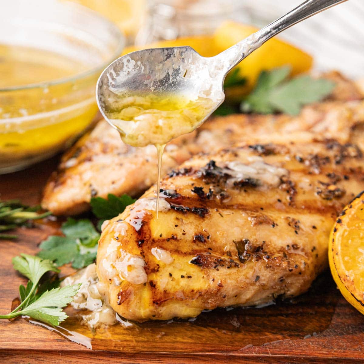 Tuscan grilled chicken after being cooked on a wooden board with parsley and lemon.