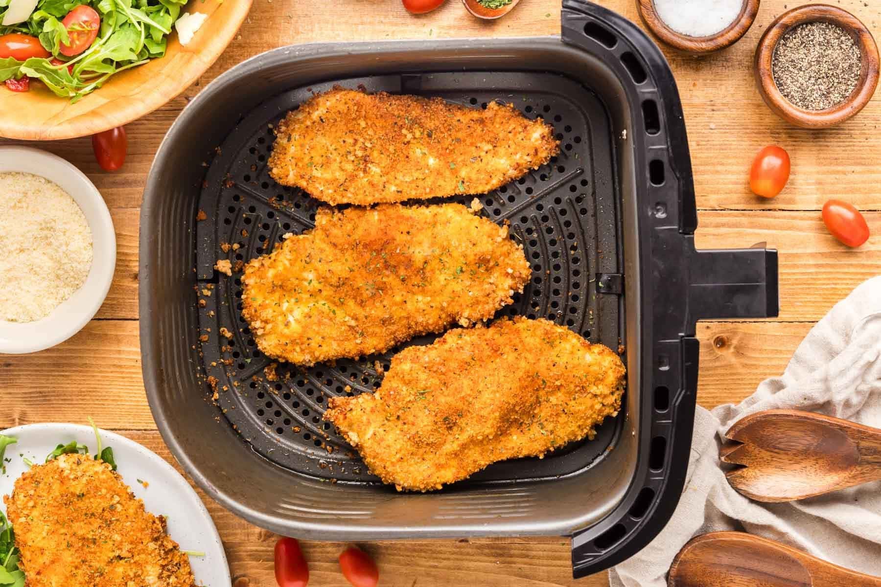 Overhead shot of finished air fryer chicken cutlets in the air fryer basket.