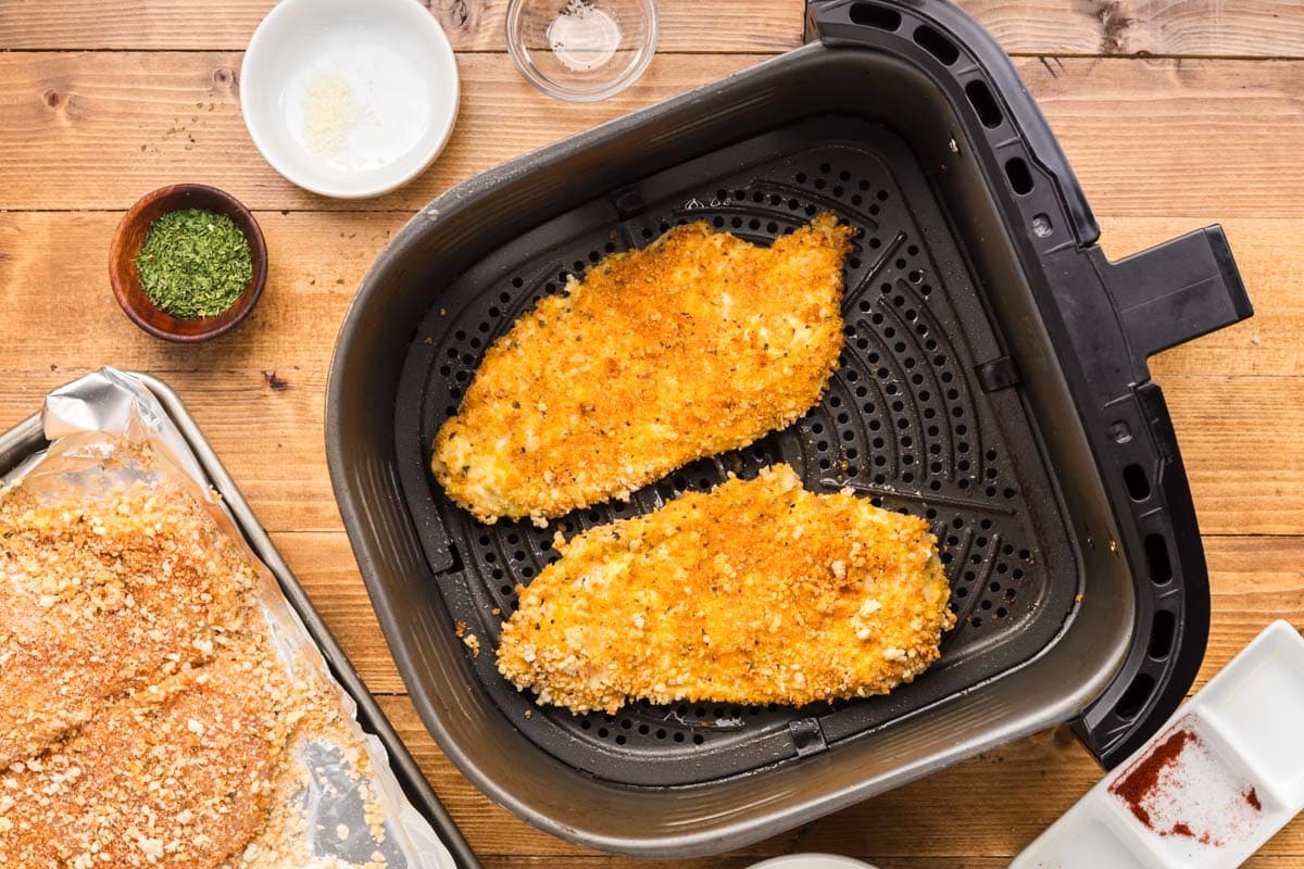 Air fryer chicken cutlets flipped over to cook on the other side.