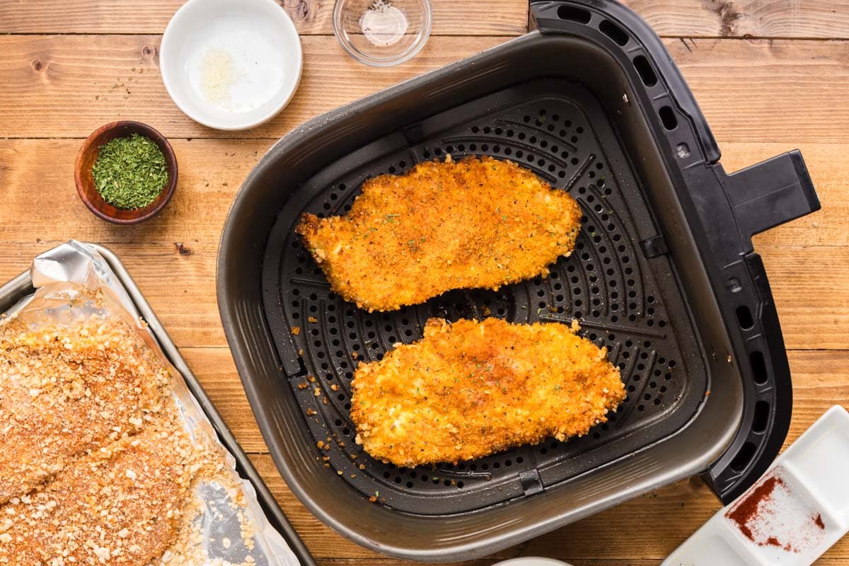 Air fryer chicken cutlets in an air fryer basket and garnished with dried parsley.