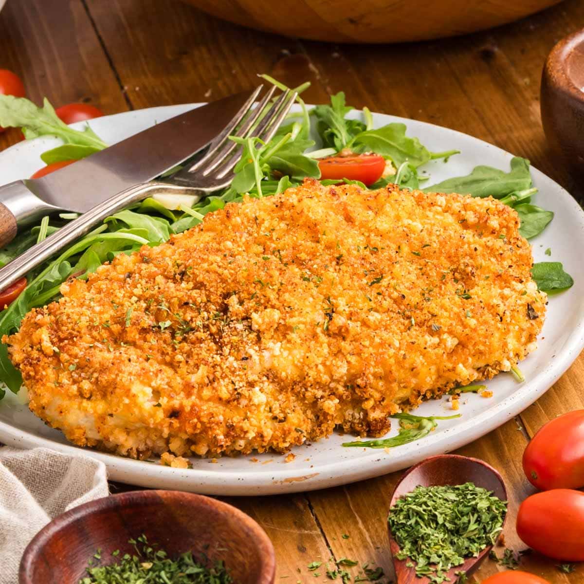 Air fryer chicken cutlet served on a plate with a side salad.