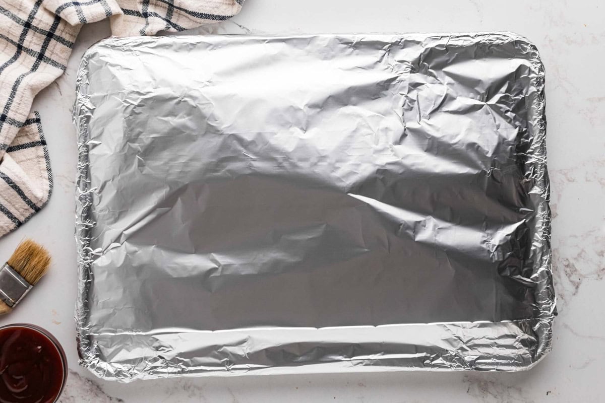 Foil wrapped tightly around ribs in baking sheet.