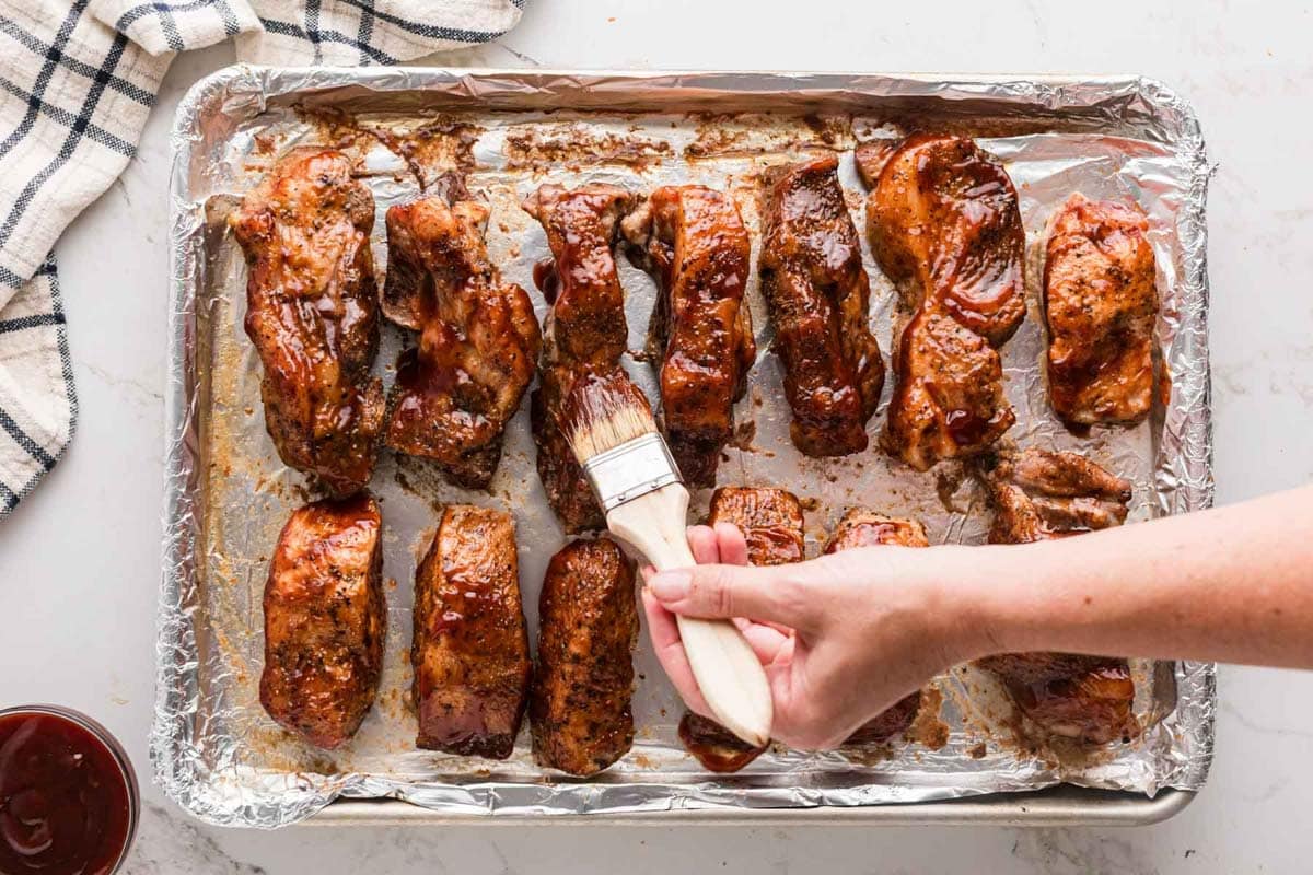 Brushing on bbq sauce on partially cooked country pork ribs.