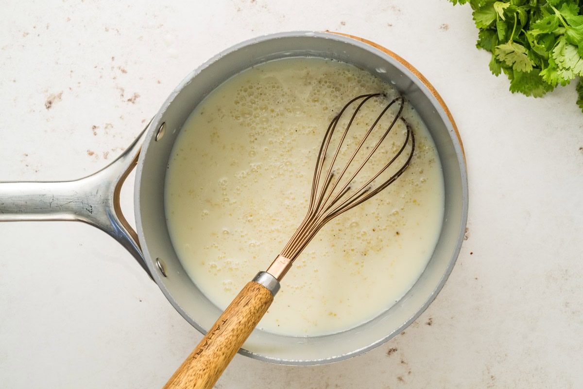 Milk added to the roux in a saucepan.