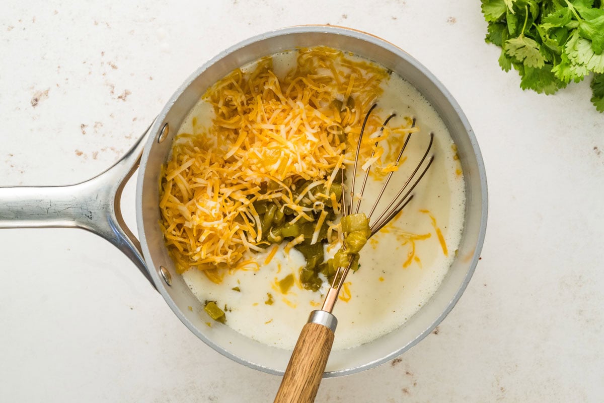 Shredded cheese and chopped green chiles added to the sauce.