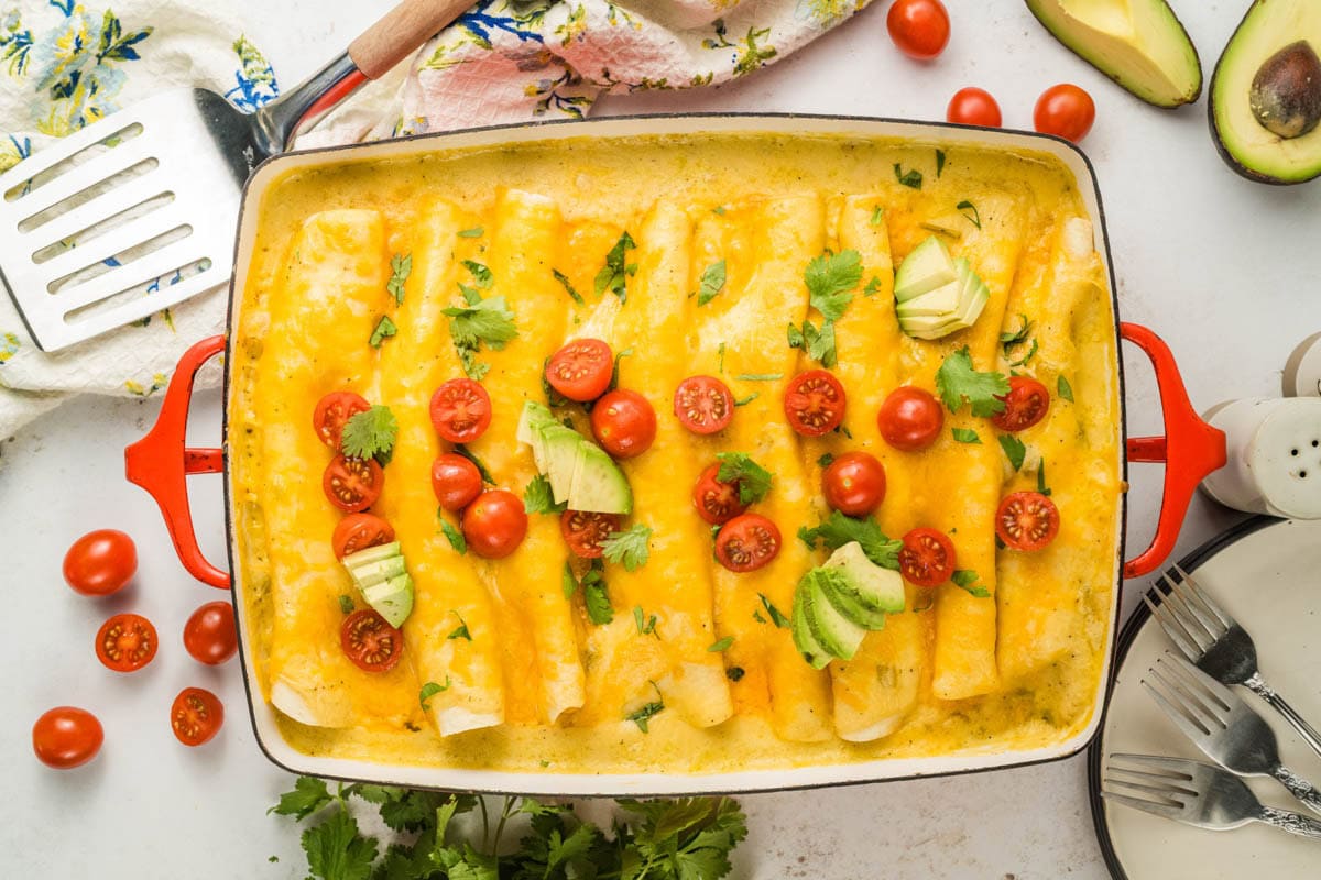 Baked breakfast enchiladas garnished with tomatoes and avocados.
