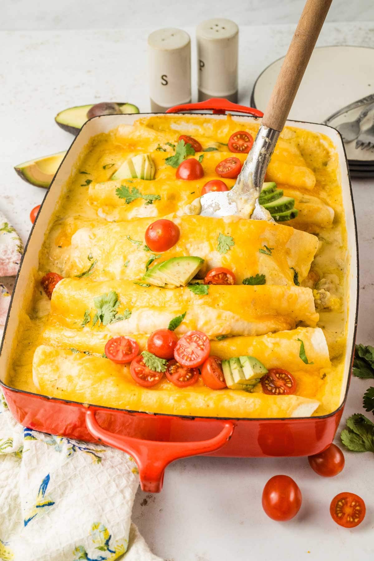 Spatula taking some breakfast enchiladas from the baking dish.