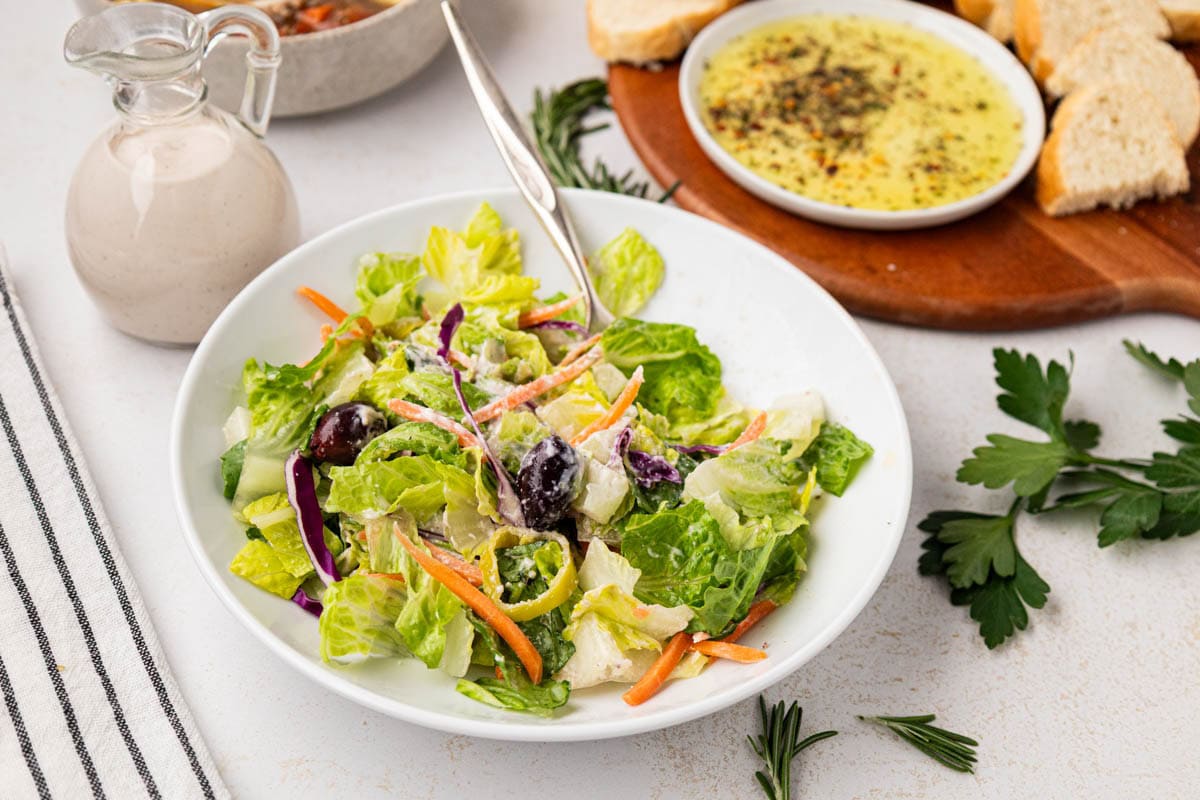 Italian House salad with creamy parmesan dressing in a white salad bowl.