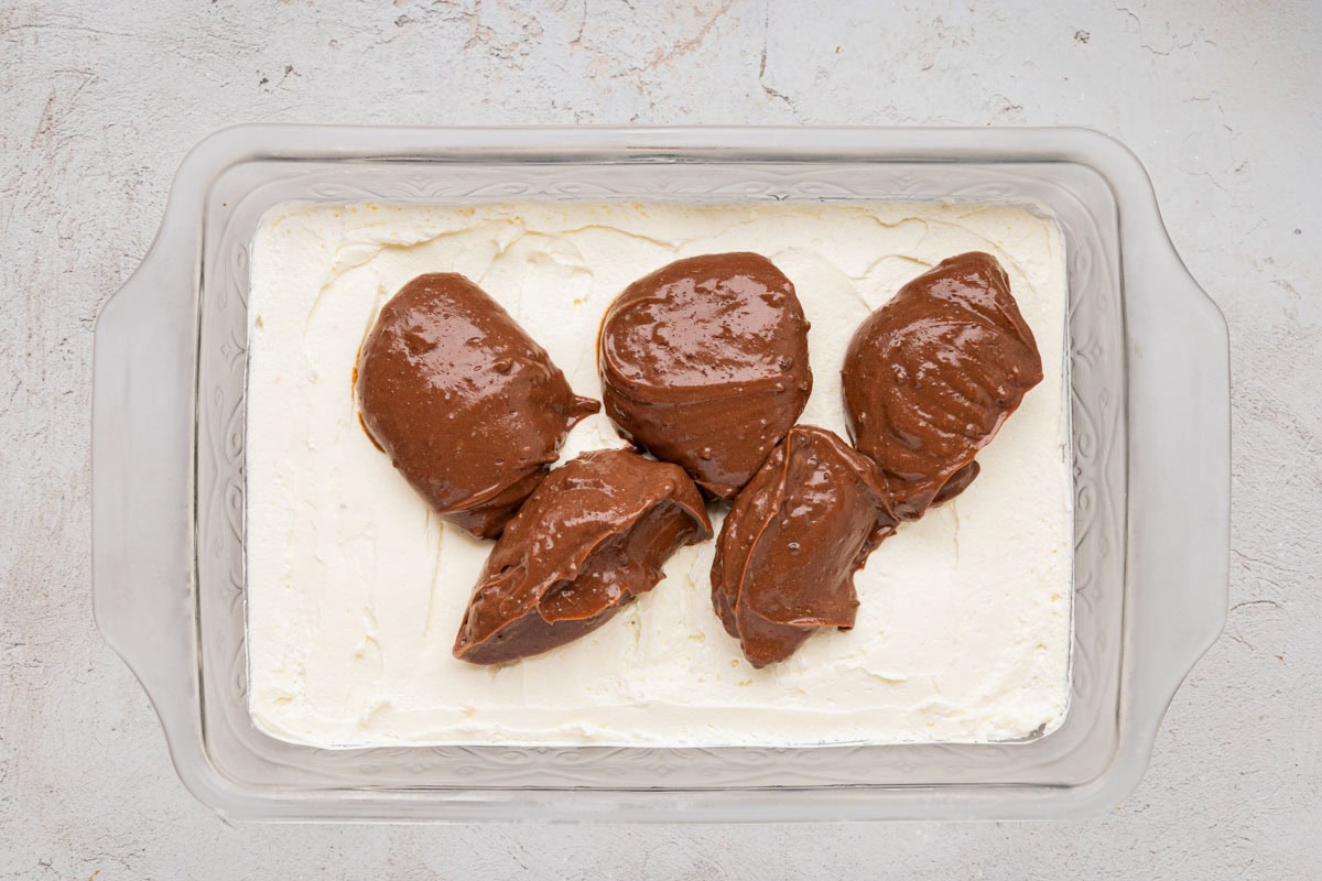 Chocolate pudding layer added on top of the cream cheese layer in a baking dish.