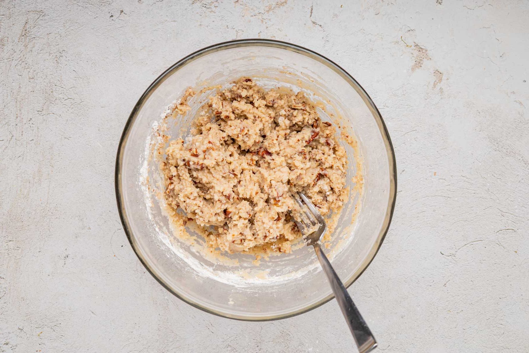 Flour, butter and nut mixture mixed together in a bowl with a fork.