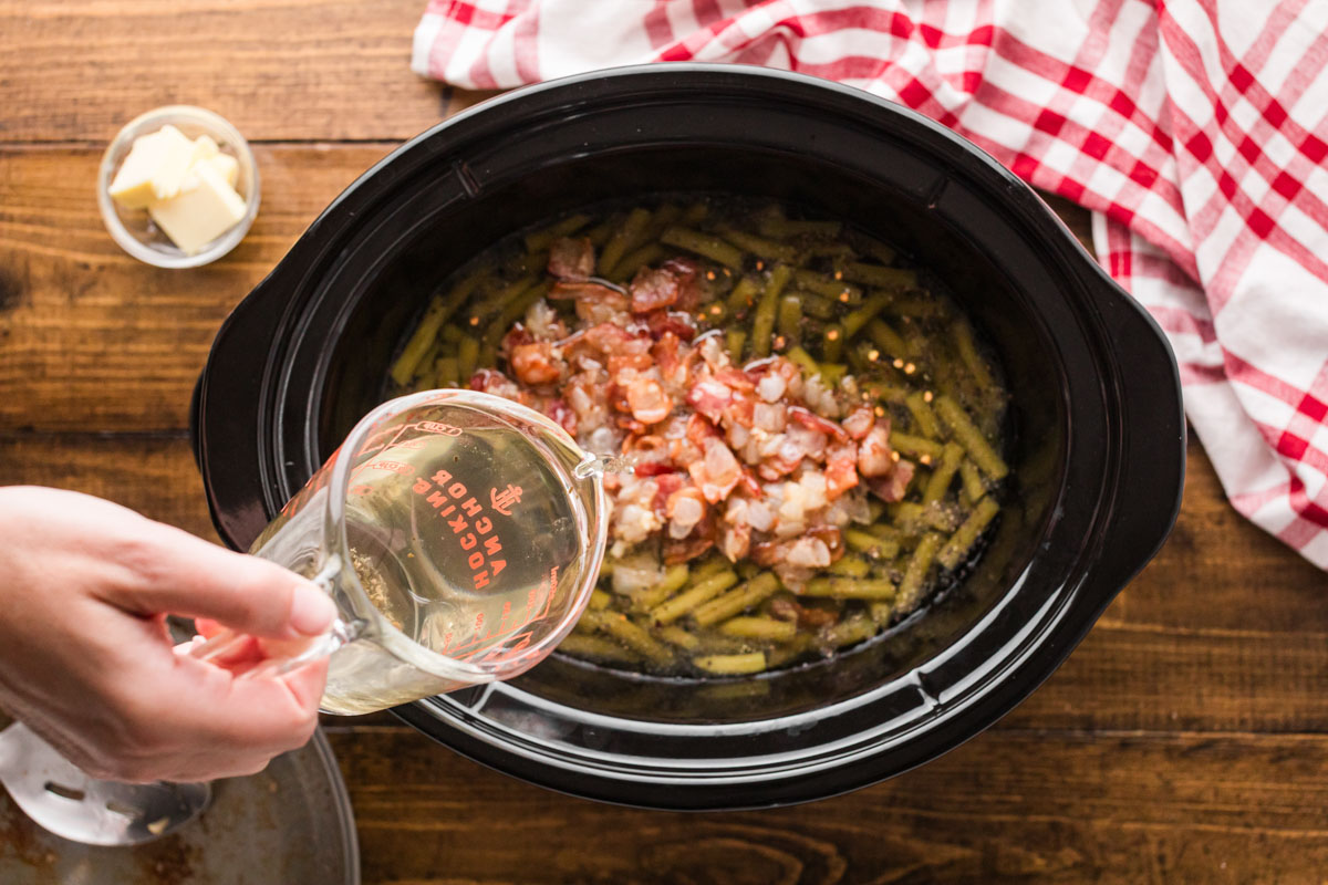 Pouring broth into the slow cooker.