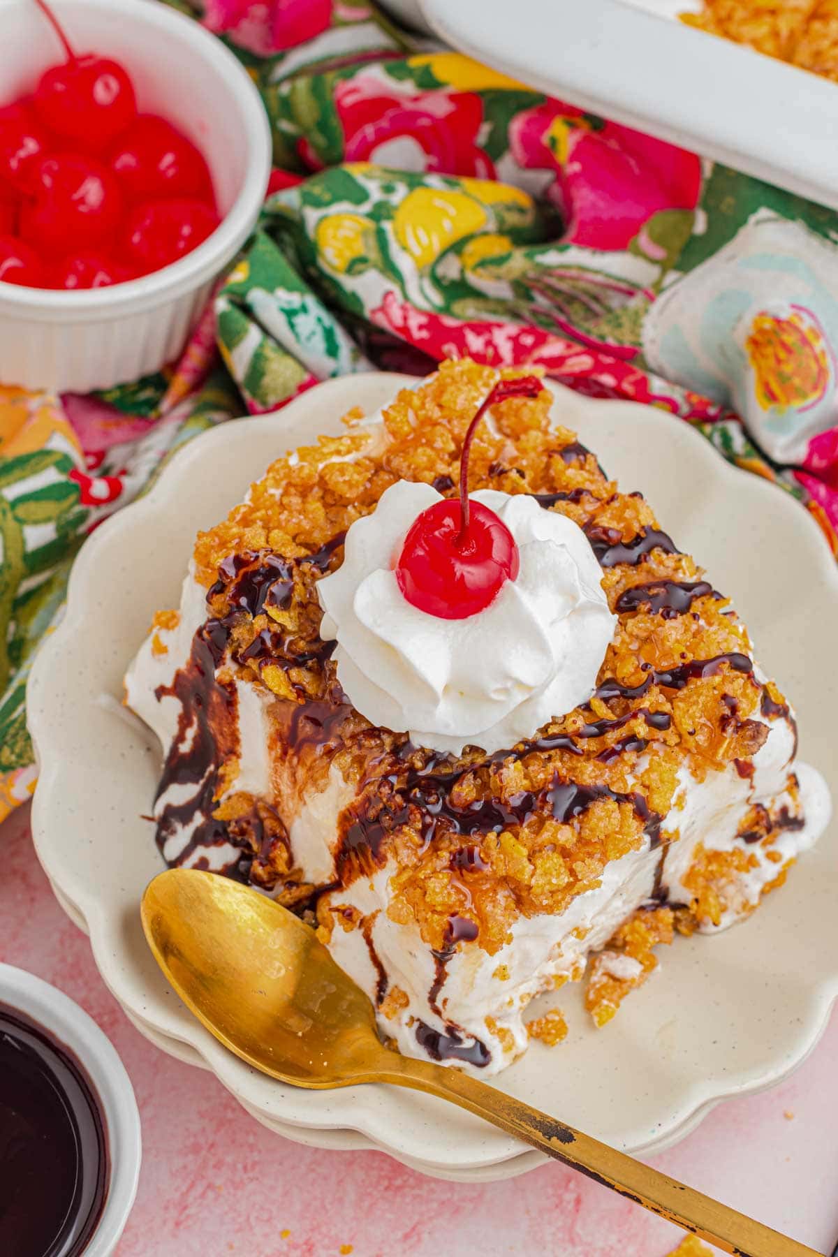 A slice of fried ice cream cake drizzle with chocolate and topped with whipped cream and a cherry.
