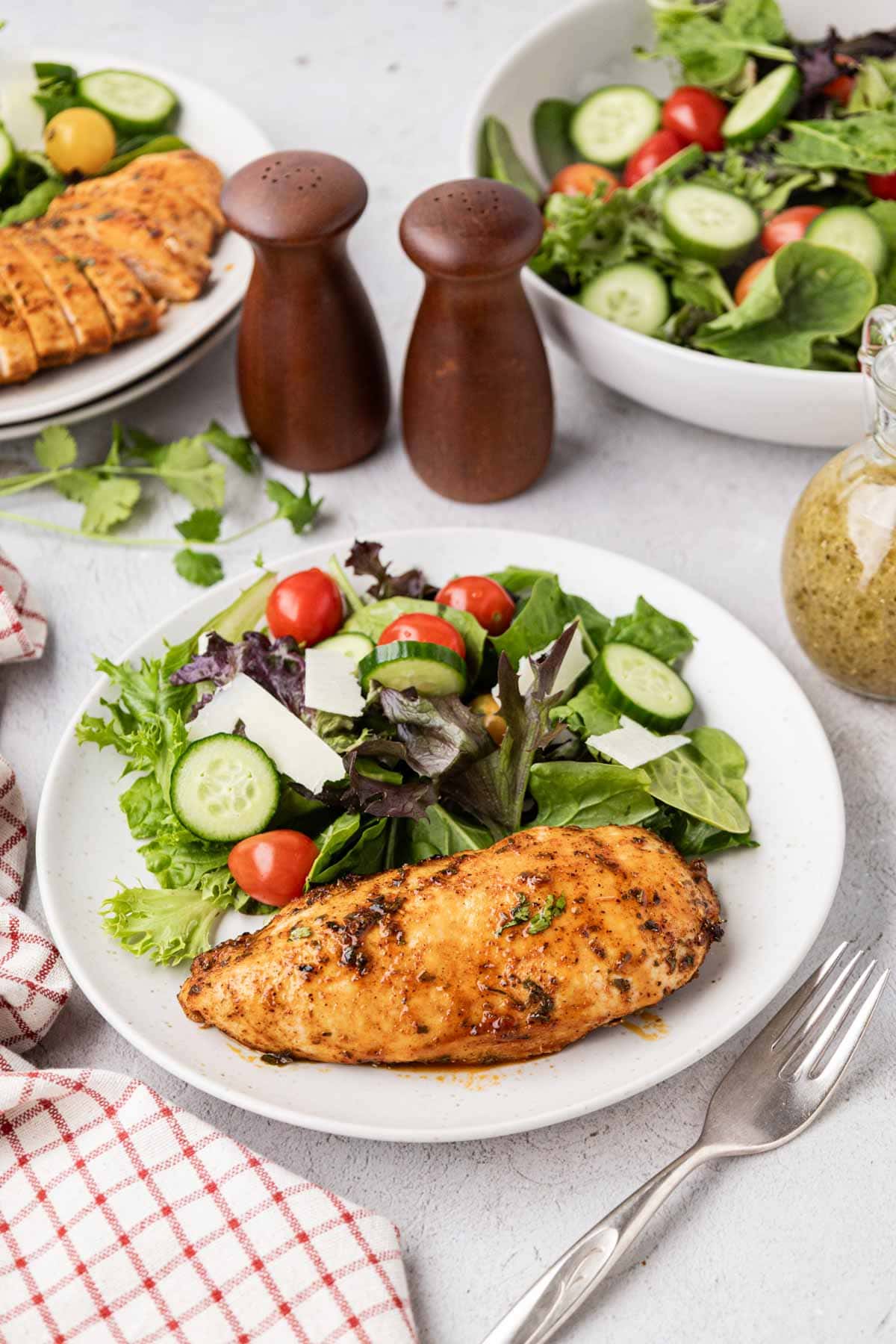 Juicy baked chicken breast on a white plate with a garden salad.