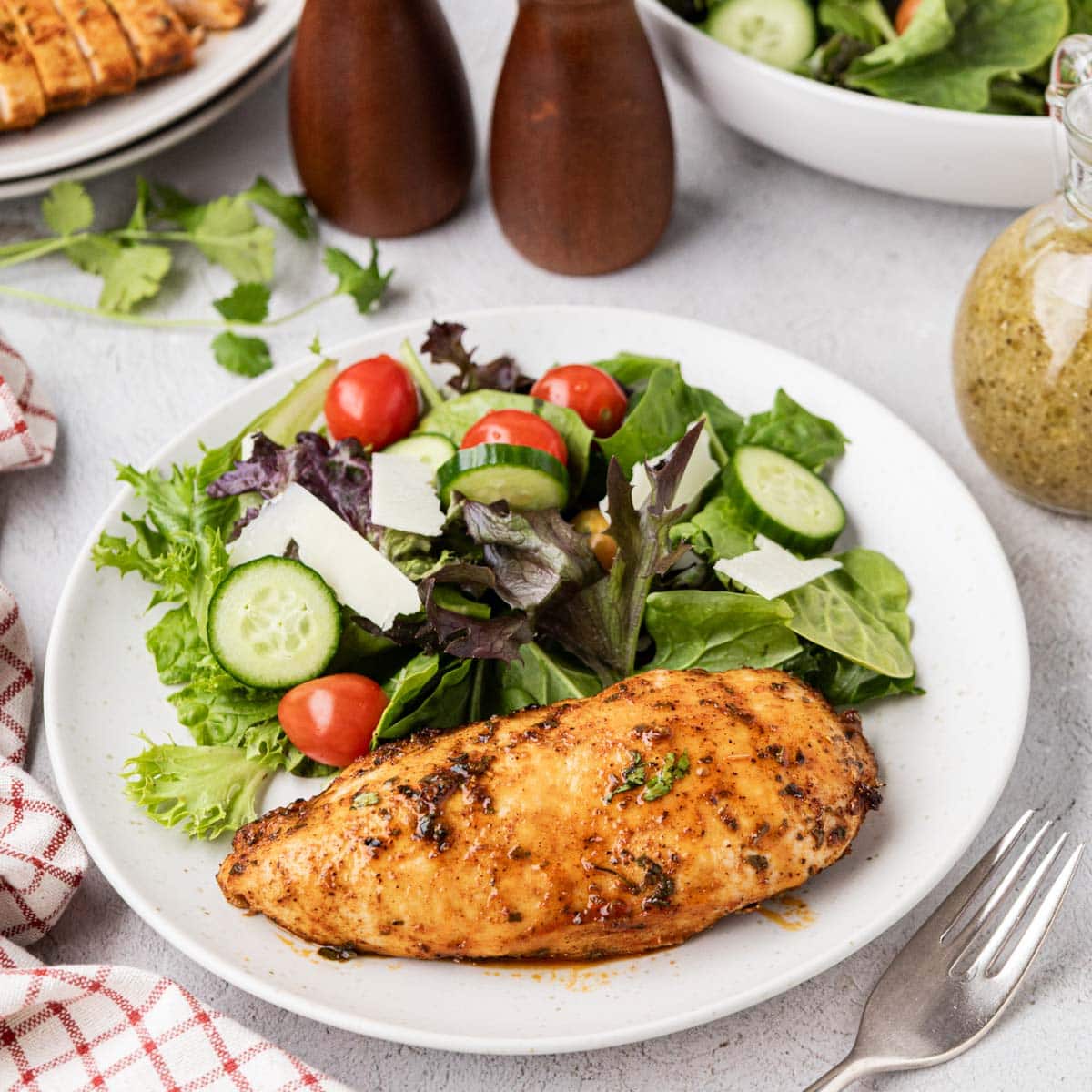Juicy oven baked chicken on a plate with a garden salad.