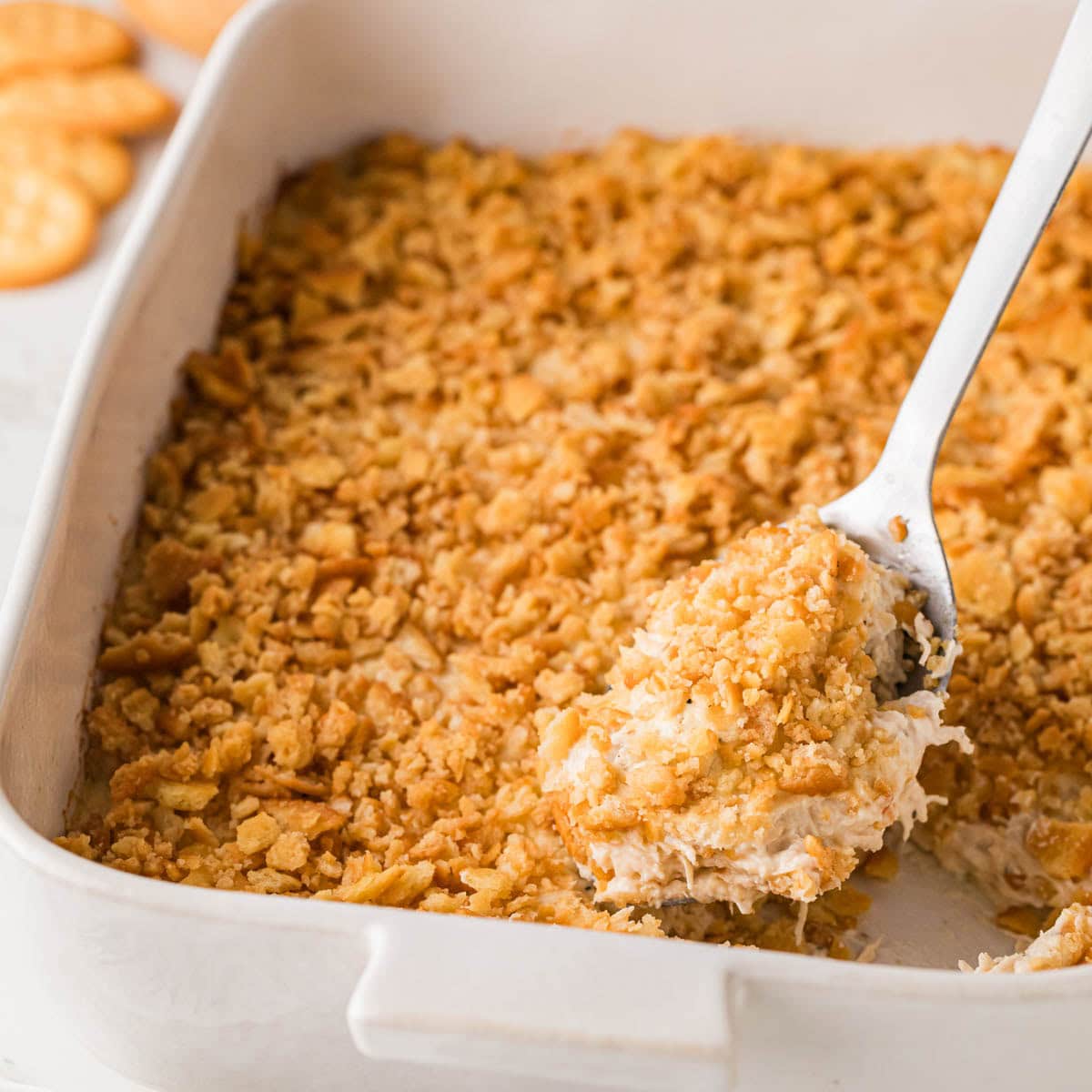 Scooping up a portion of Ritz cracker chicken casserole from a baking dish.