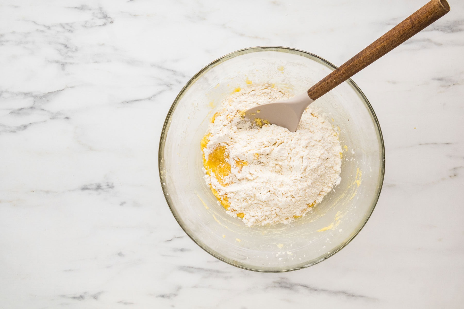 Adding dry ingredients into the butter mixture in a bowl.