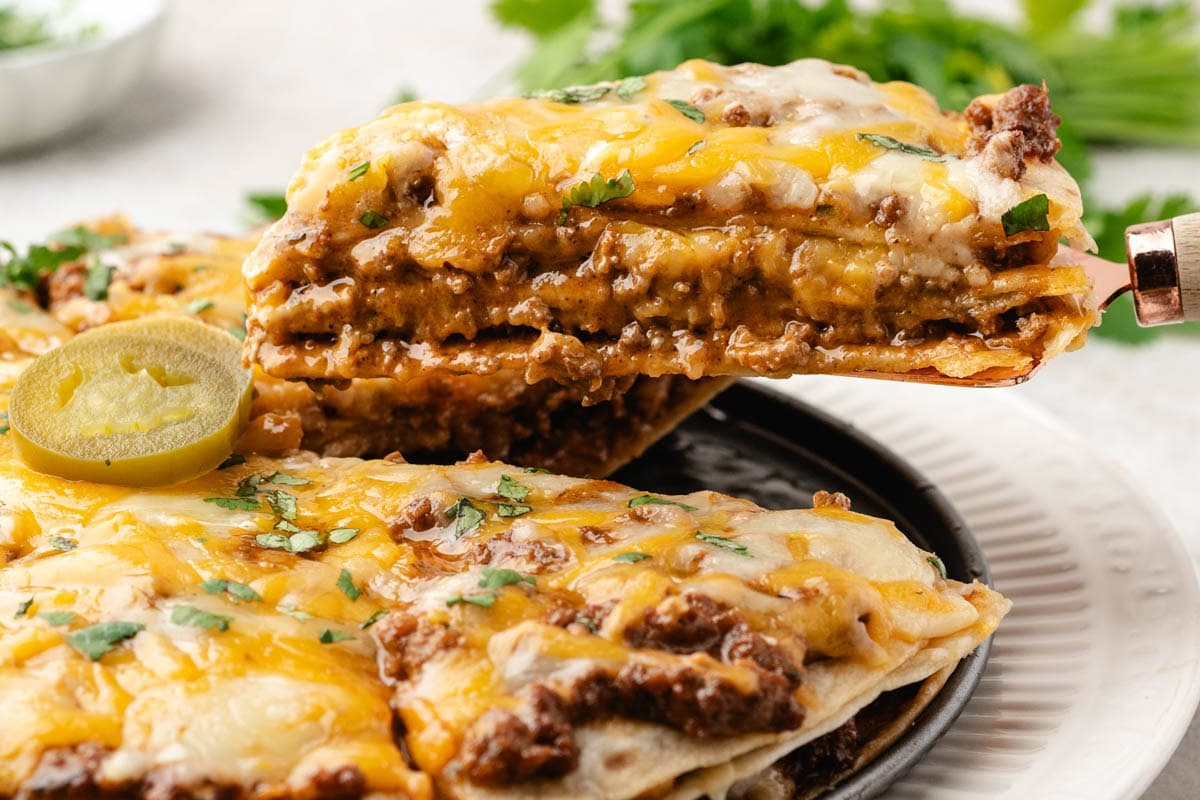 Removing a slice of taco casserole from the pan with a spatulata.