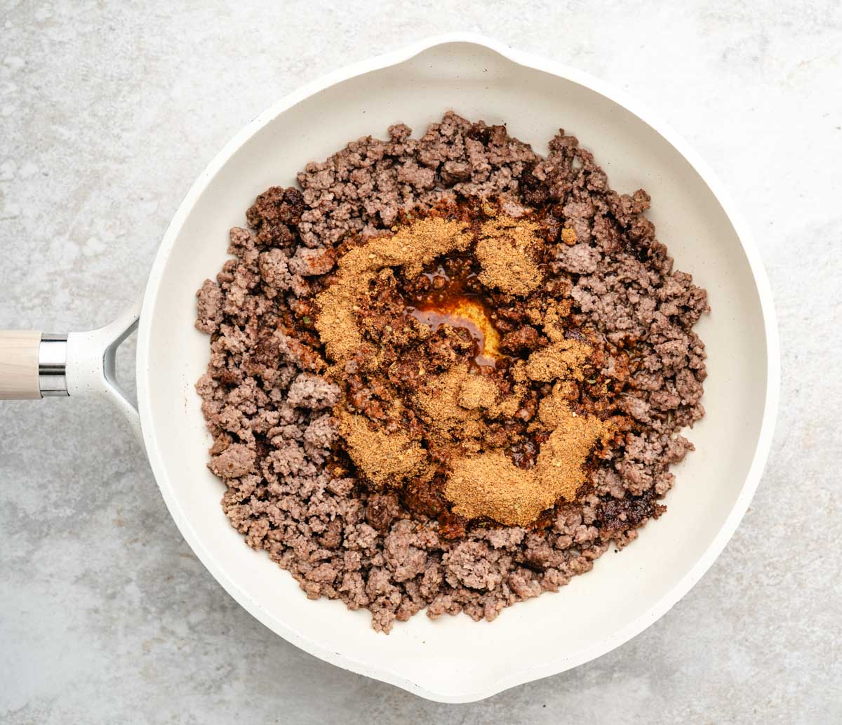 Seasoning the ground beef with taco seasoning in a skillet.