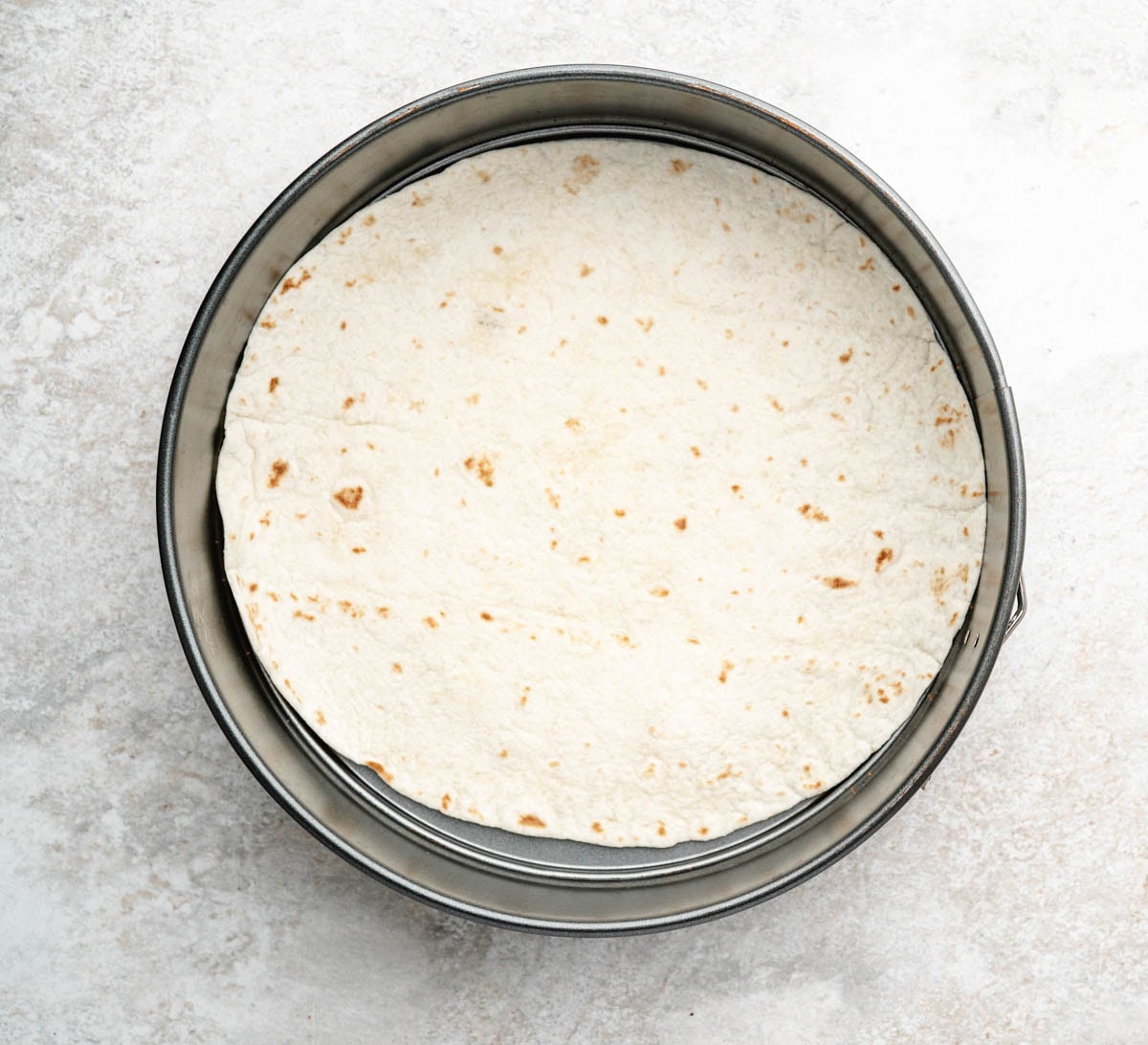 Tortilla in the bottom of a spring form pan.
