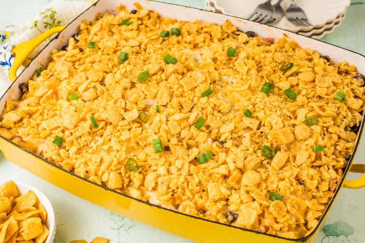 Baked Tex Mex chicken noodle casserole in a yellow baking dish, with green onions as garnish.