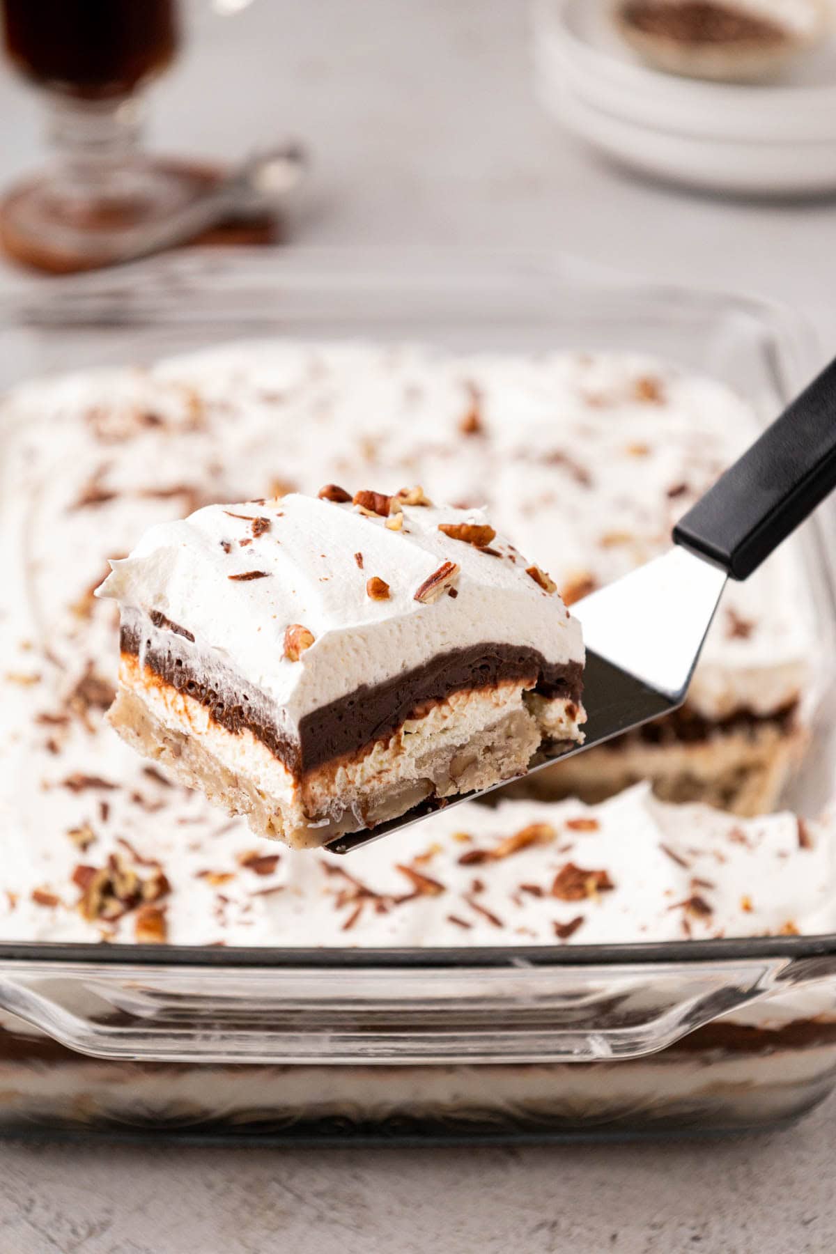 Removing a slice of chocolate lush dessert from the baking dish with a spatula.