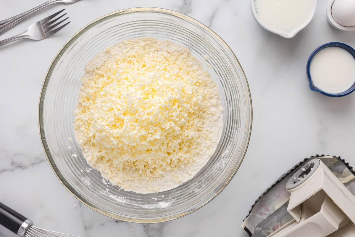 Frozen grated butter added to the dry ingredients in a bowl.