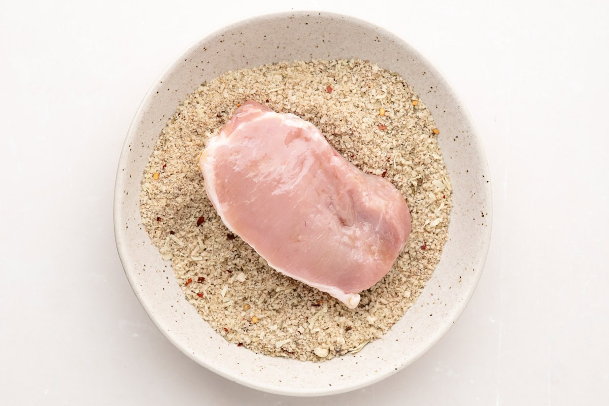 Dipping a pork chop into the panko mixture.