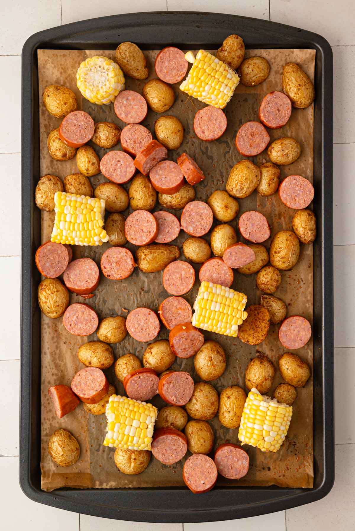 Sausage and corn added to the sheet pan.
