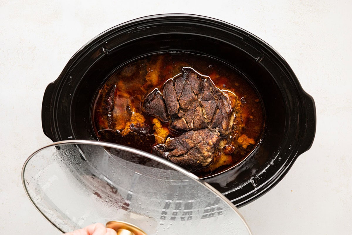 Removing lid from the slow cooker.